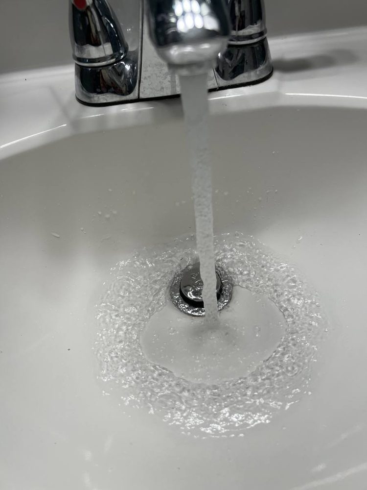 Water swirling freely down a cleared white bathroom sink drain