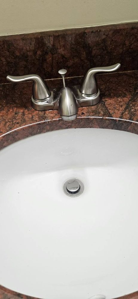Brushed nickel two-handle faucet installed on a white sink in a granite counter