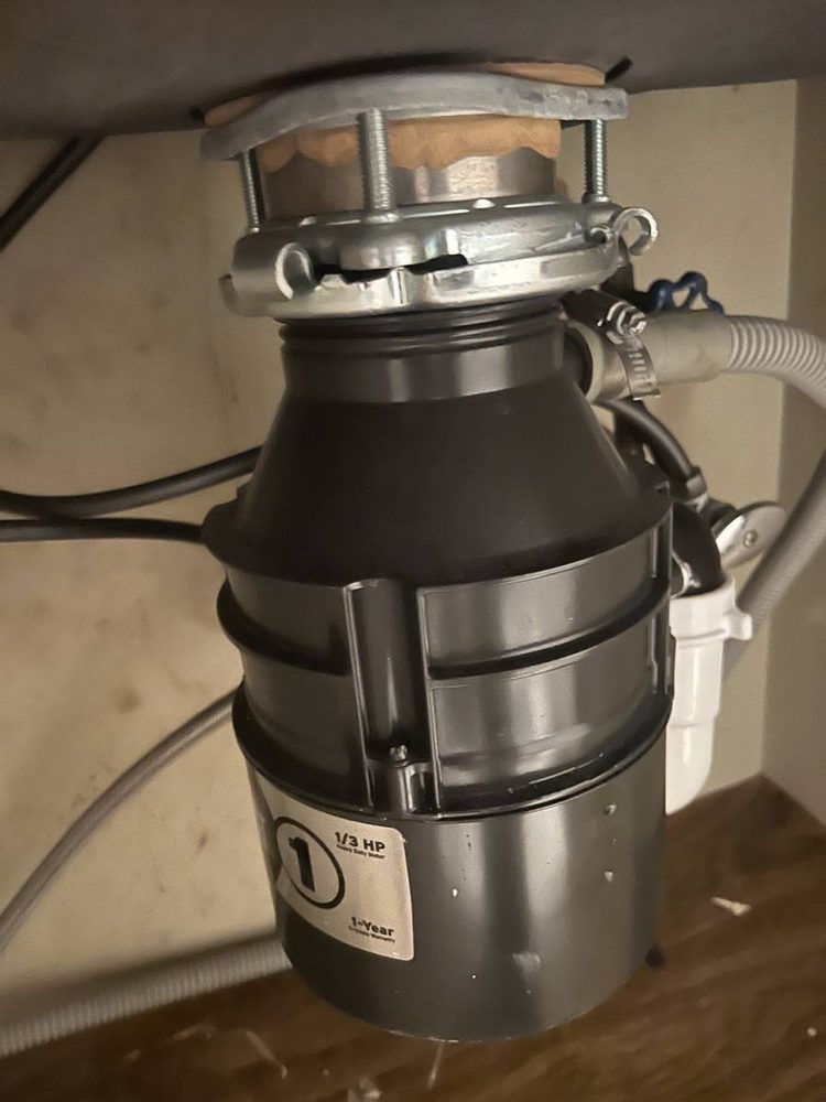 Stainless garbage disposal mounted under a kitchen sink