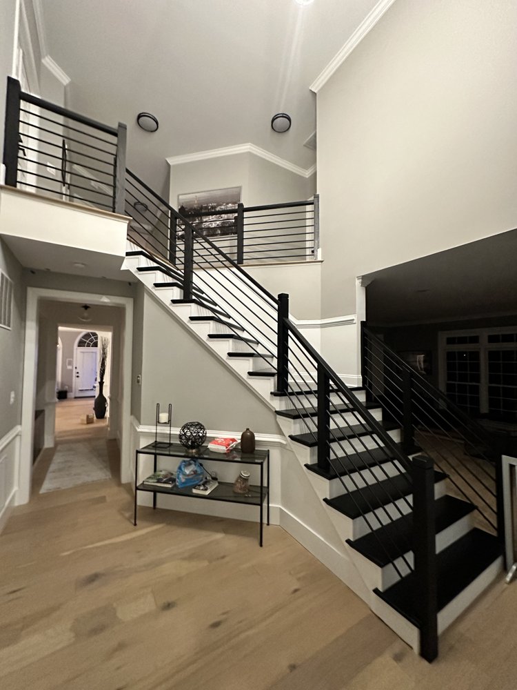 Black metal handrail with horizontal bars along a staircase with dark treads