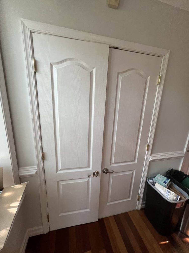 Pair of white arched-panel interior doors installed in a hallway with hardwood floors