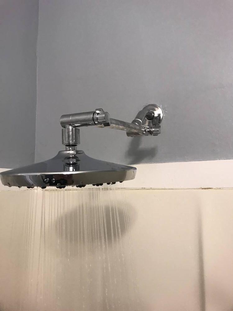 Rain shower head running on an angled arm