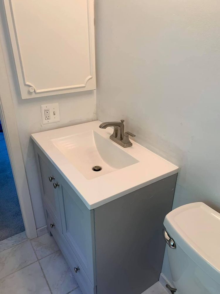 Gray bathroom vanity with a white sink top and faucet installed